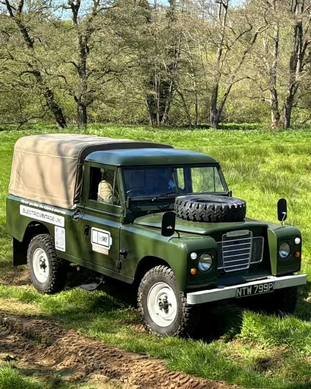 Our green Land Rover with its canvas top, standing in the long grass on a sunny day